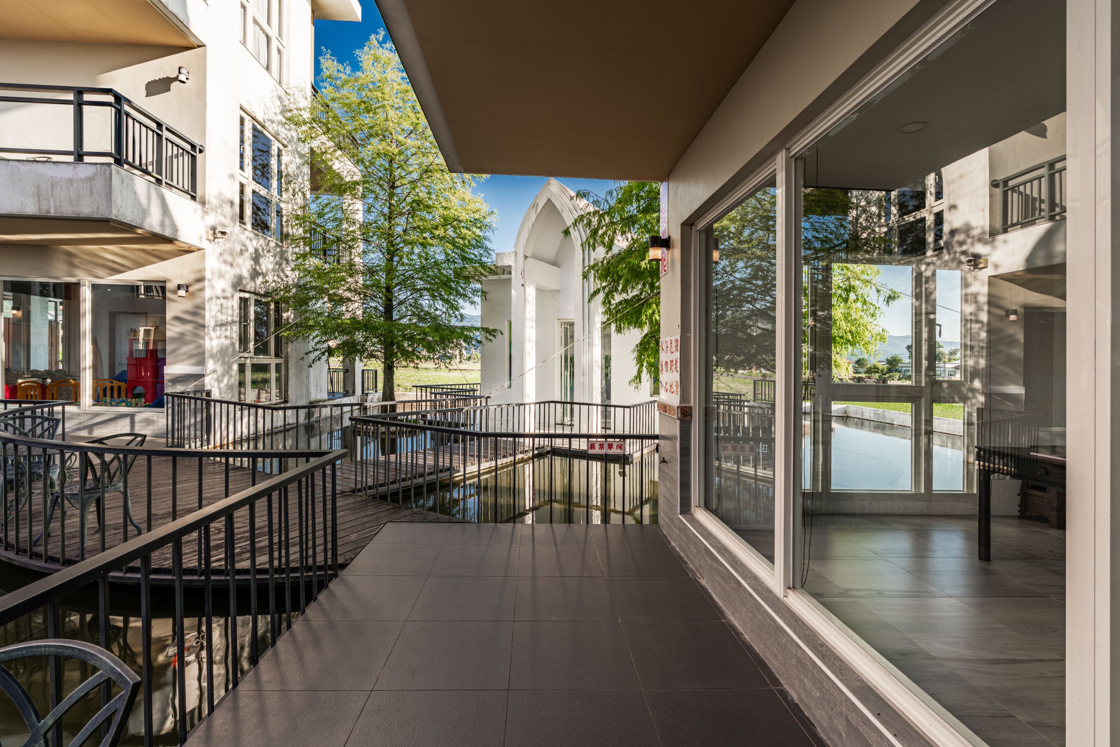 A hotel corridor with a glass wall offering a view of a body of water and greenery.