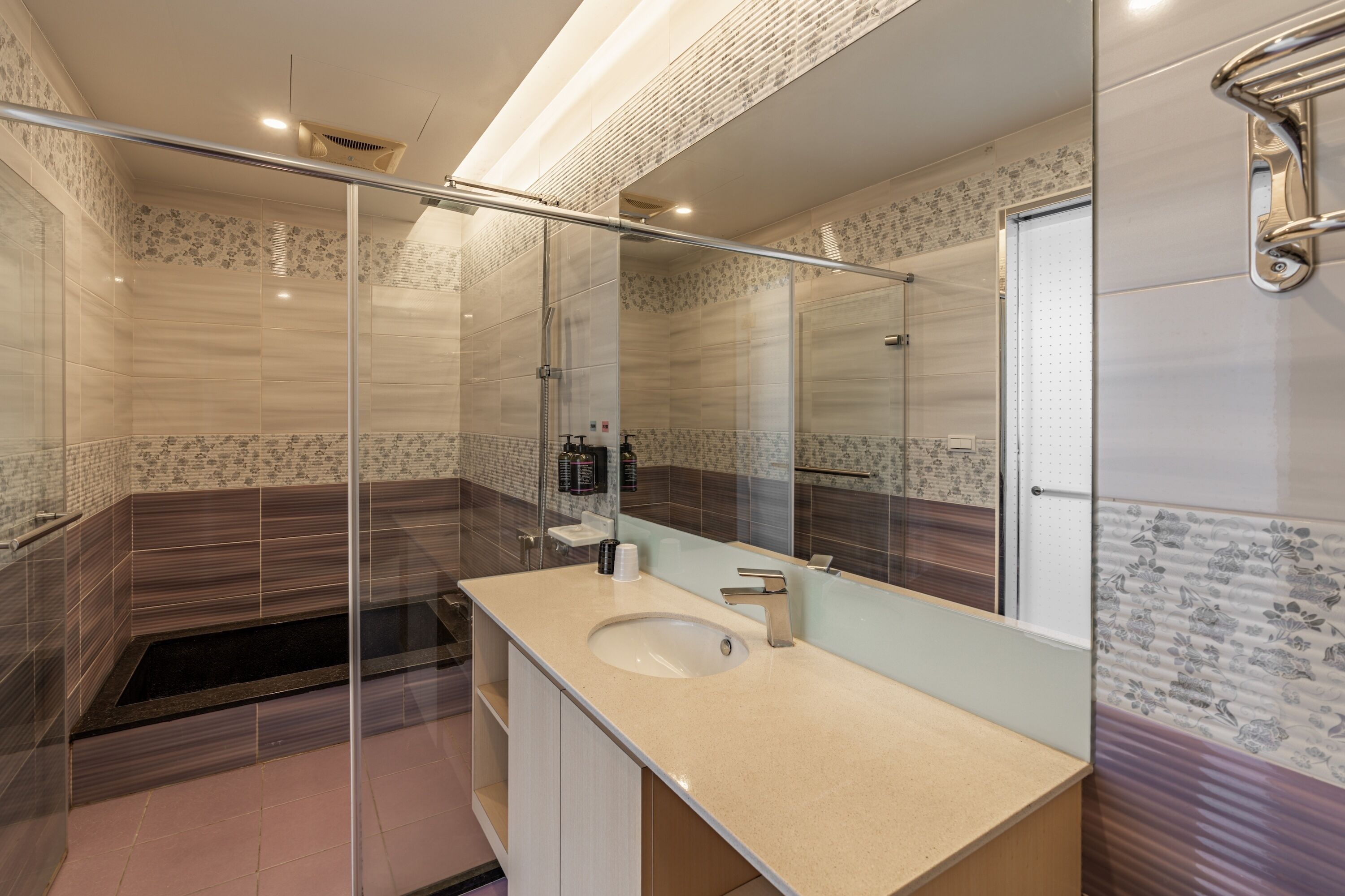 Un baño moderno con ducha de mampara de vidrio, lavamanos con espejo y bañera.