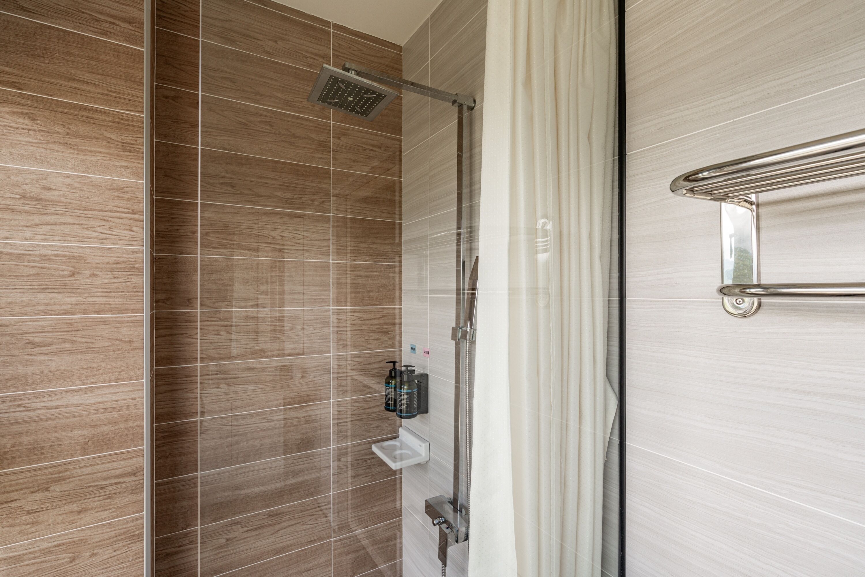 A shower with a rain showerhead, a glass door, and a towel rack.