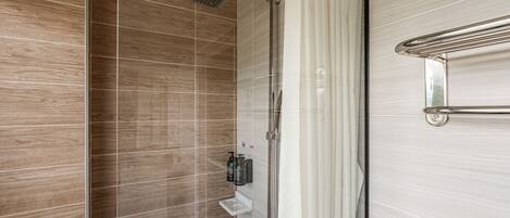 A shower with a rain showerhead, a glass door, and a towel rack.
