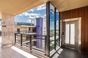 A modern apartment with a balcony, large windows, and a view of the city.