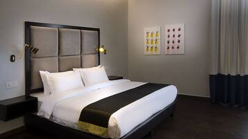 A neatly made bed with a headboard, a bedside table with a lamp, and two wall art pieces.