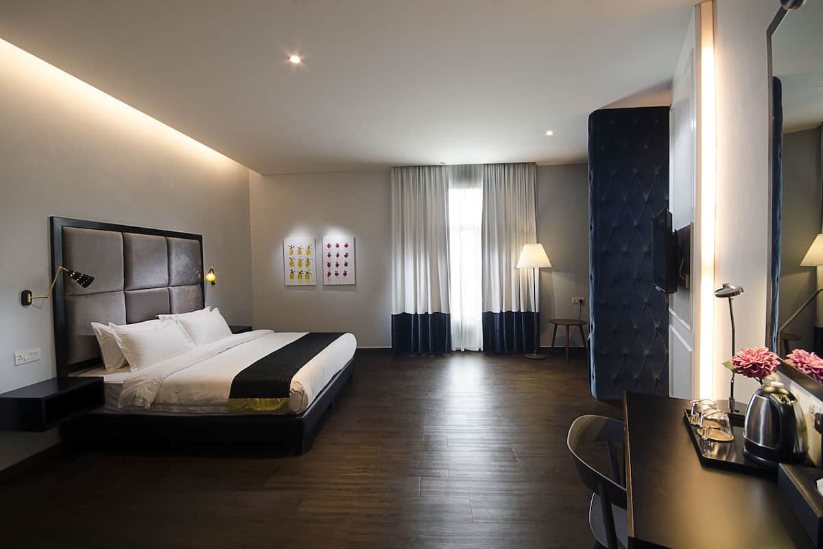 A modern hotel room with a large bed, a desk with a lamp, and a large mirror.