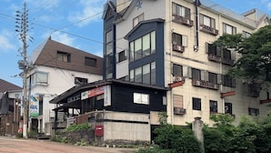 Un immeuble à plusieurs étages comprenant des logements et des espaces commerciaux, doté de balcons, de grandes fenêtres et d’une enseigne bien visible.
