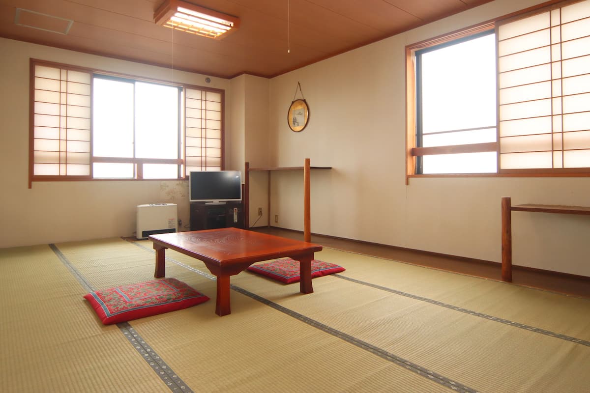 A traditional Japanese room with tatami flooring, a low wooden table, and sliding doors.