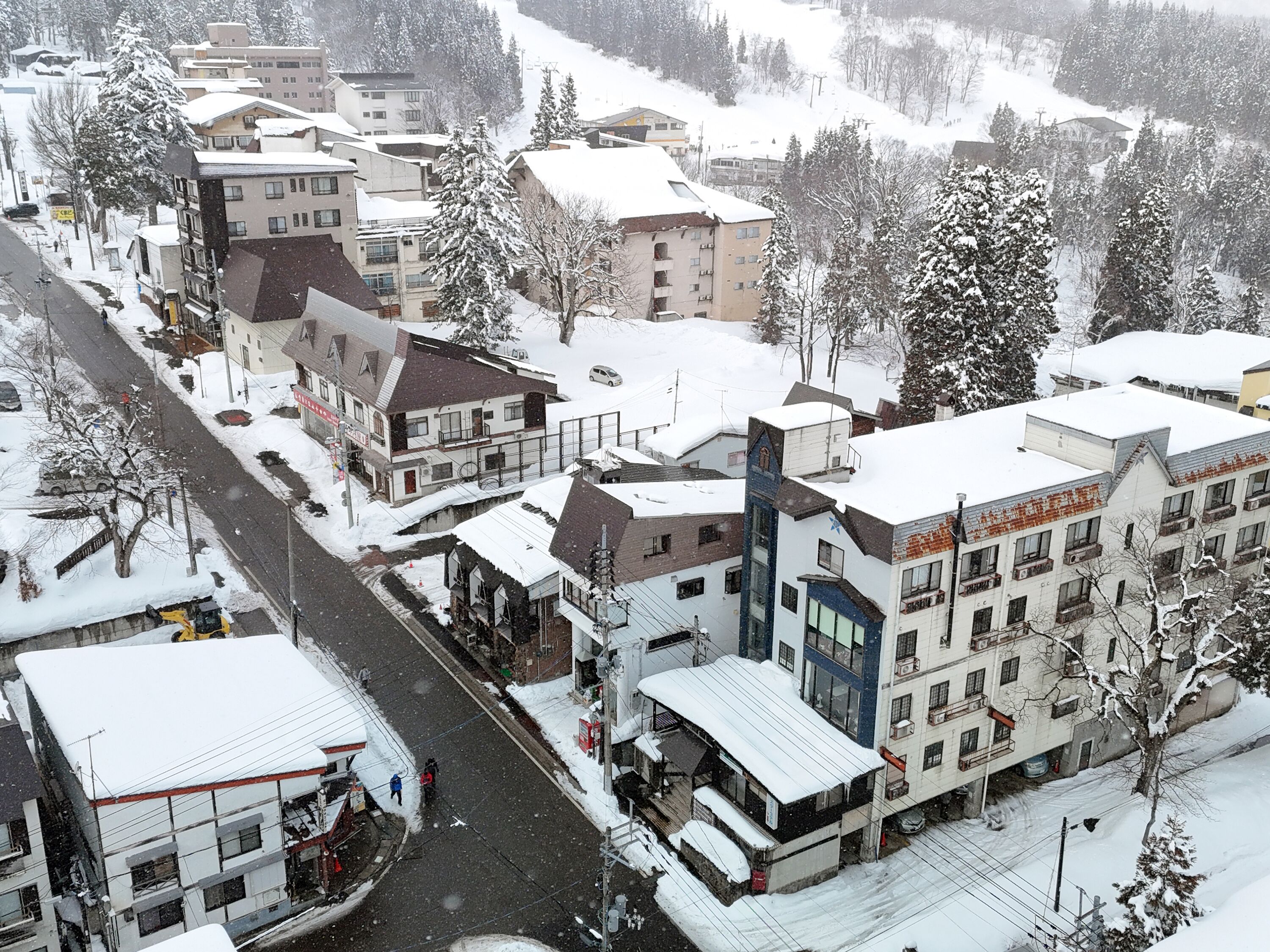 A snow-covered town with buildings, including a hotel with multiple floors and balconies.