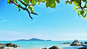A beach with clear turquoise water, rocky shore, and distant mountains. - Rawai Ka Villa with Private Pool (Rawai)