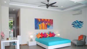 Un dormitorio con cama, mesitas de noche, ventilador de techo y un cuadro en la pared.
