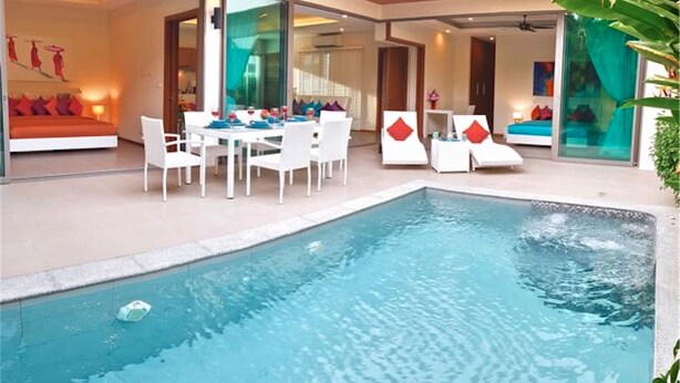 Una habitación de hotel moderna con piscina, un comedor con mobiliario blanco y una sala de estar con sofá y sillones.