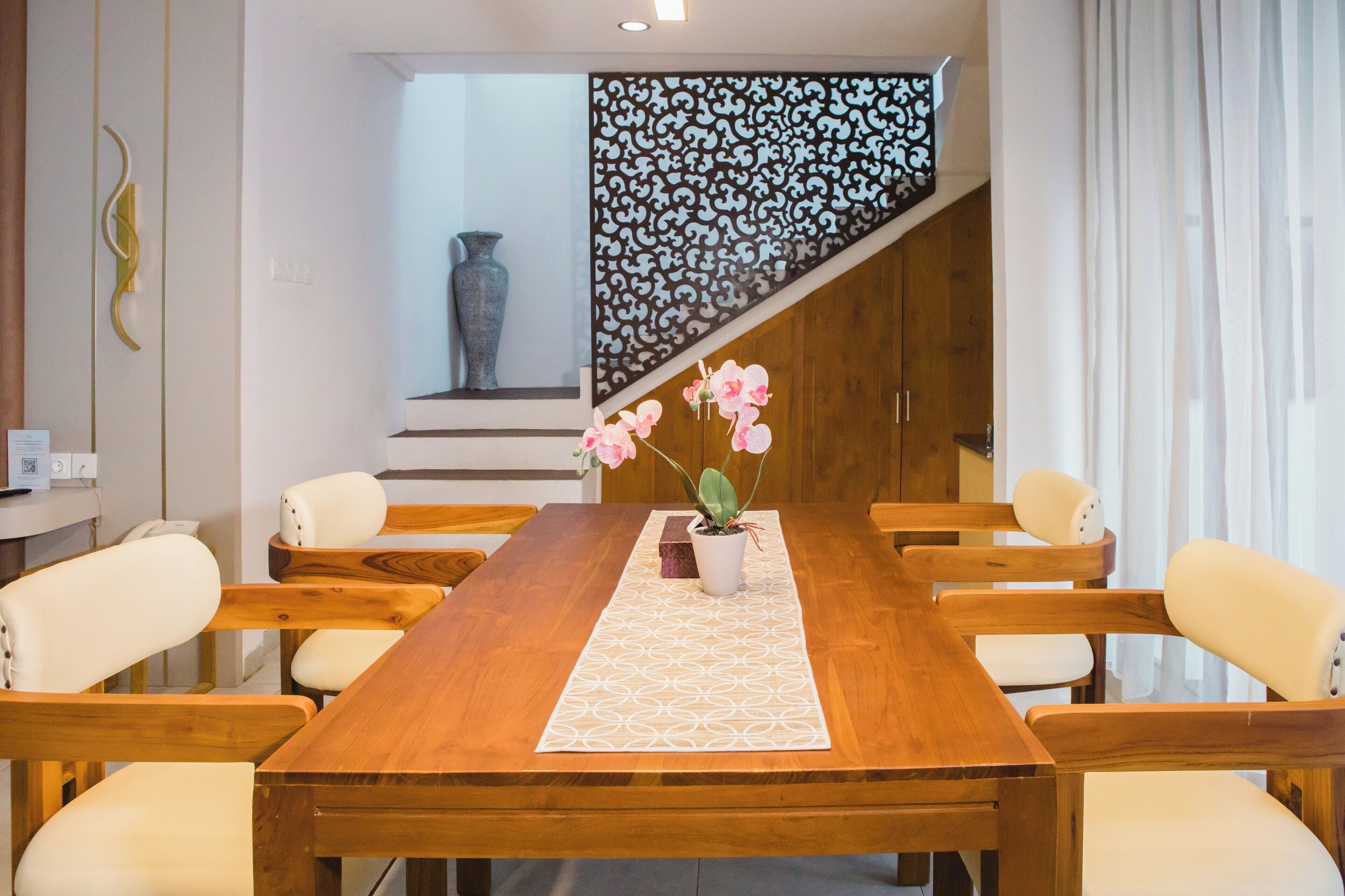A dining area with a wooden table, white chairs, and a potted orchid.