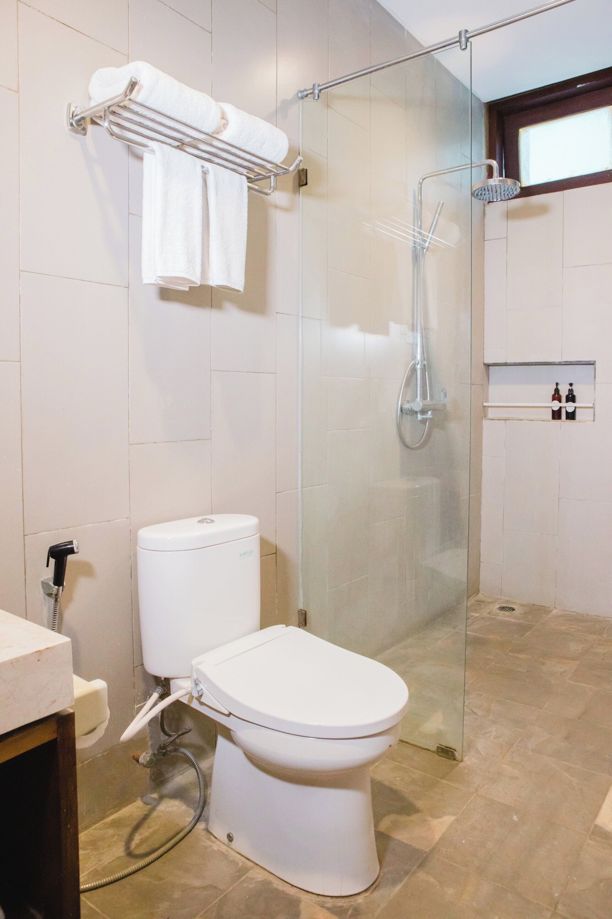 Un baño moderno con ducha de vidrio, inodoro y perchero para toallas.