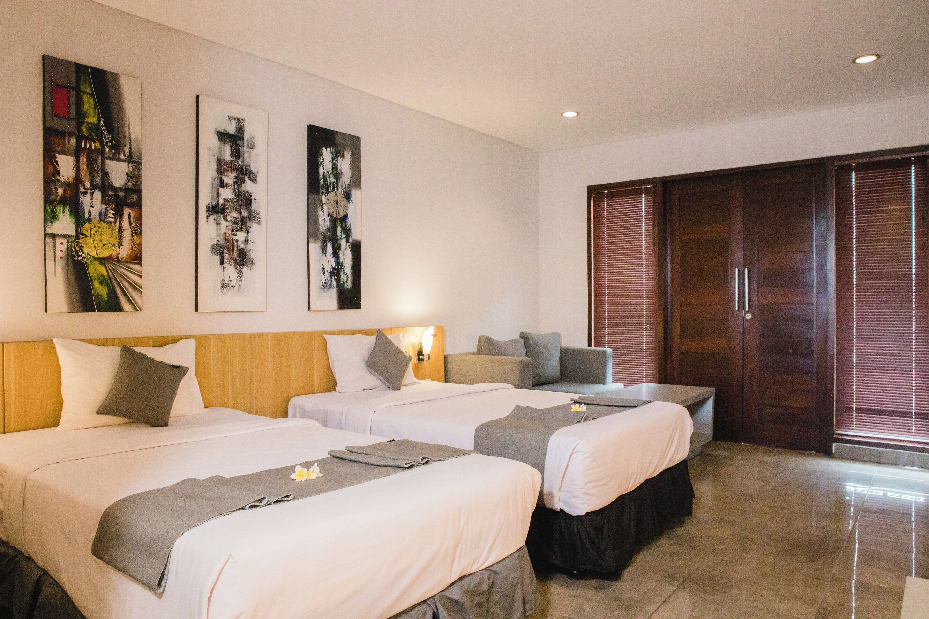 A hotel room with two beds, a sofa, and a sliding door closet.