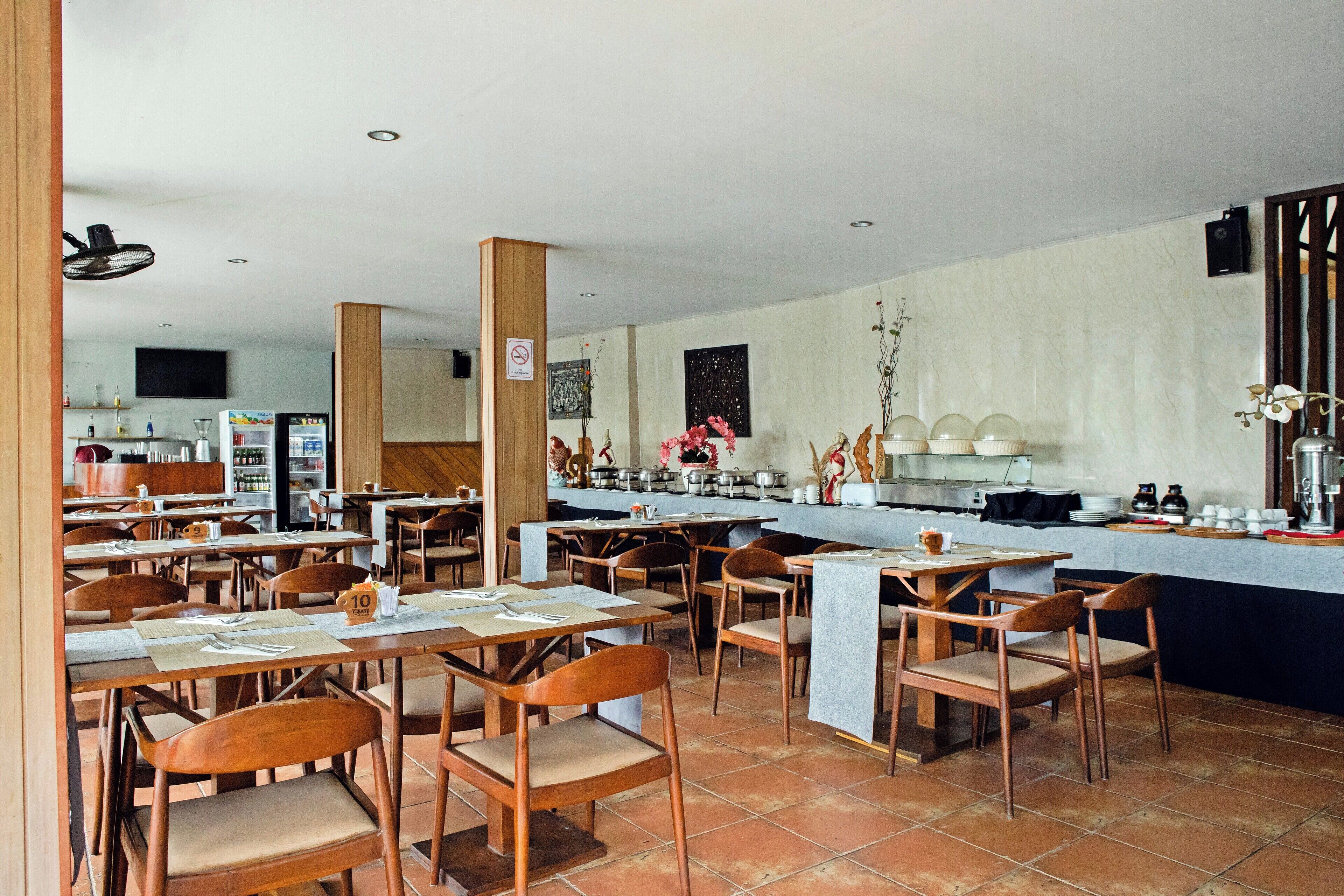 A restaurant with multiple tables and chairs, a kitchen area, and a counter with various items.