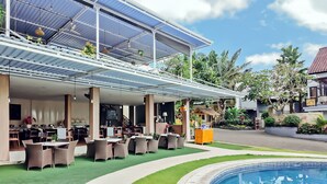 Un restaurant amb terrassa, piscina i zona coberta amb plantes.