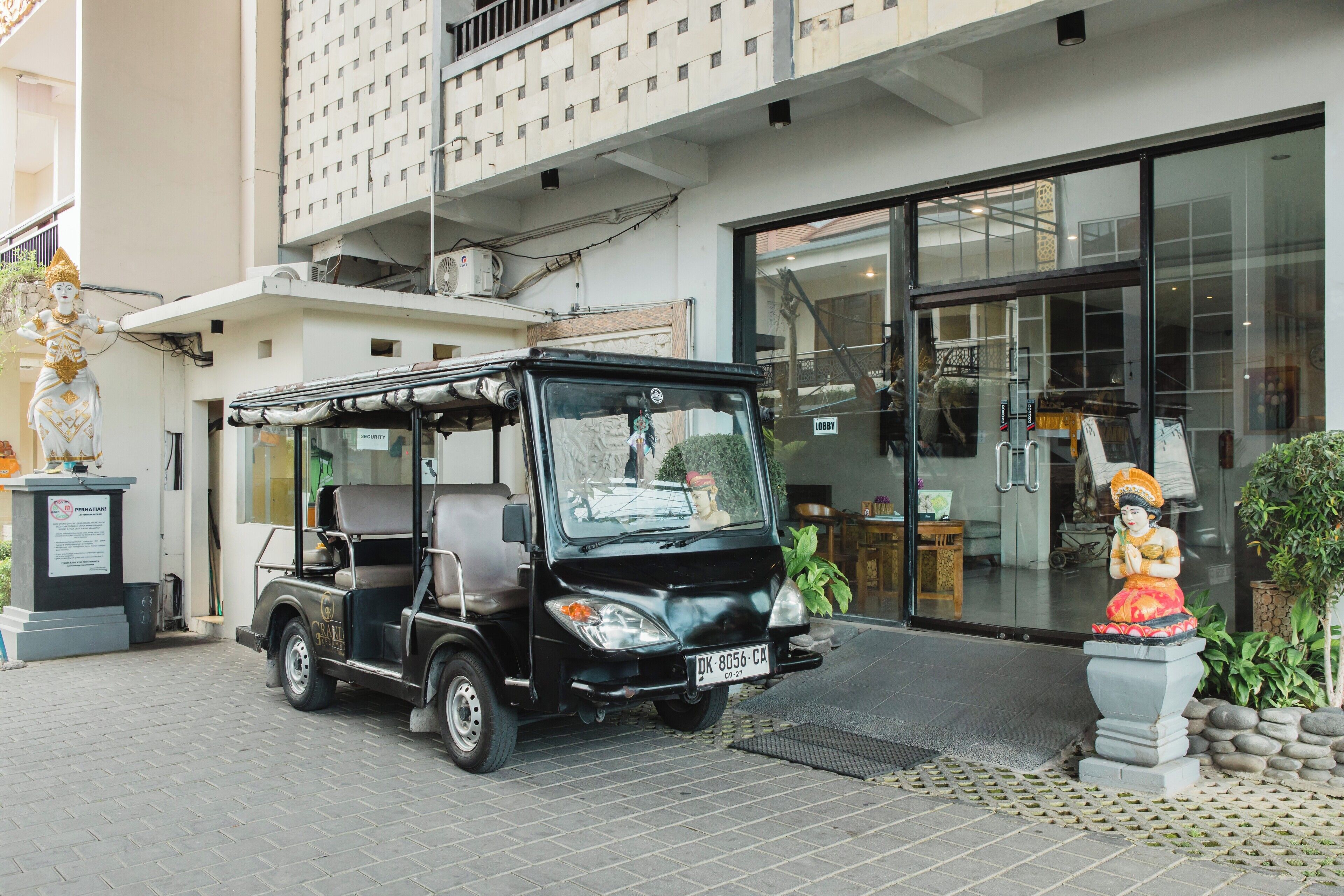 A black golf cart parked in front of a building with a large glass entrance.