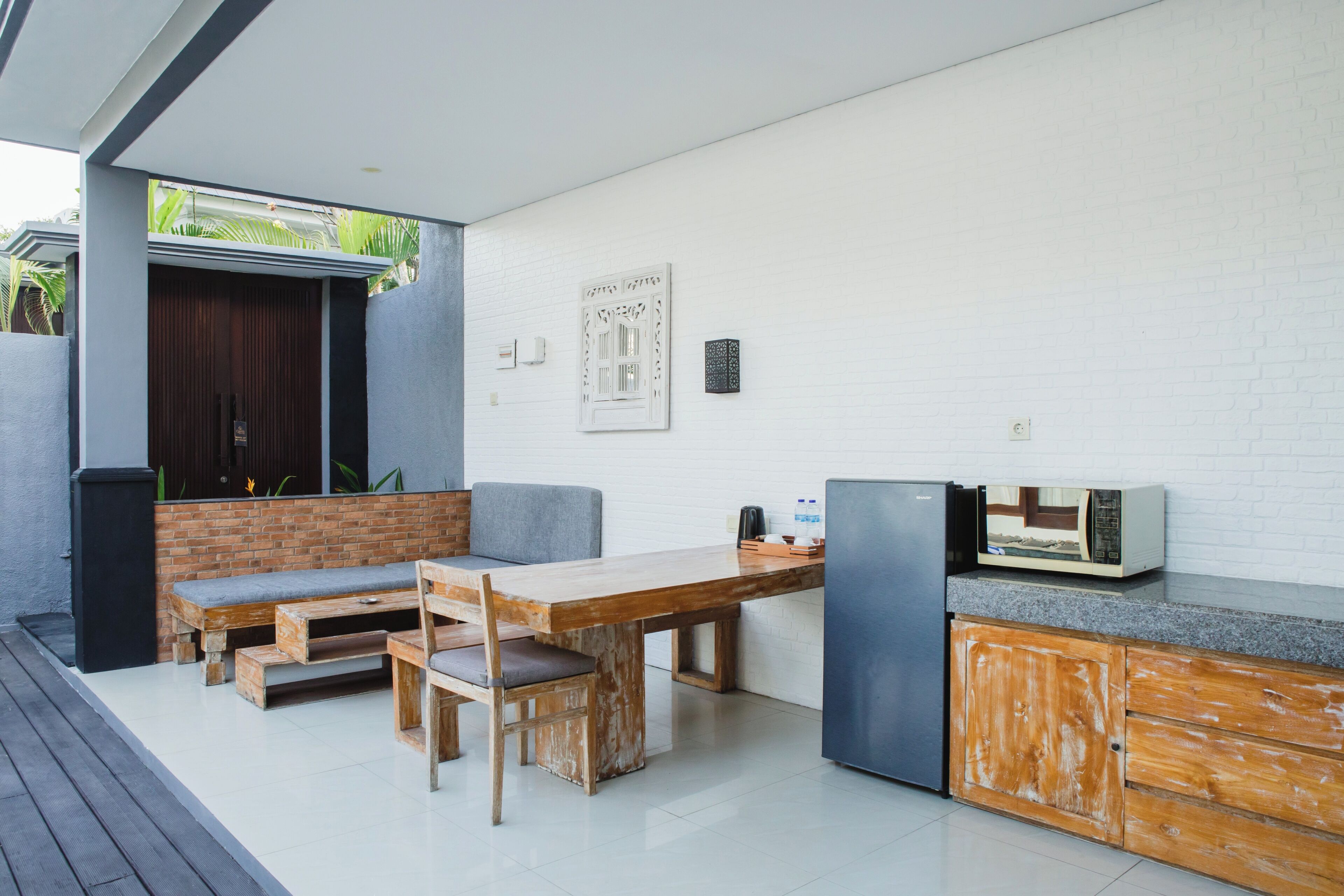 Uma cozinha moderna com mesa de jantar de madeira, bancos embutidos, geladeira e micro-ondas.