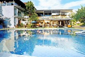 Un hotel moderno con piscina, zona de estar al aire libre y exuberante vegetación.