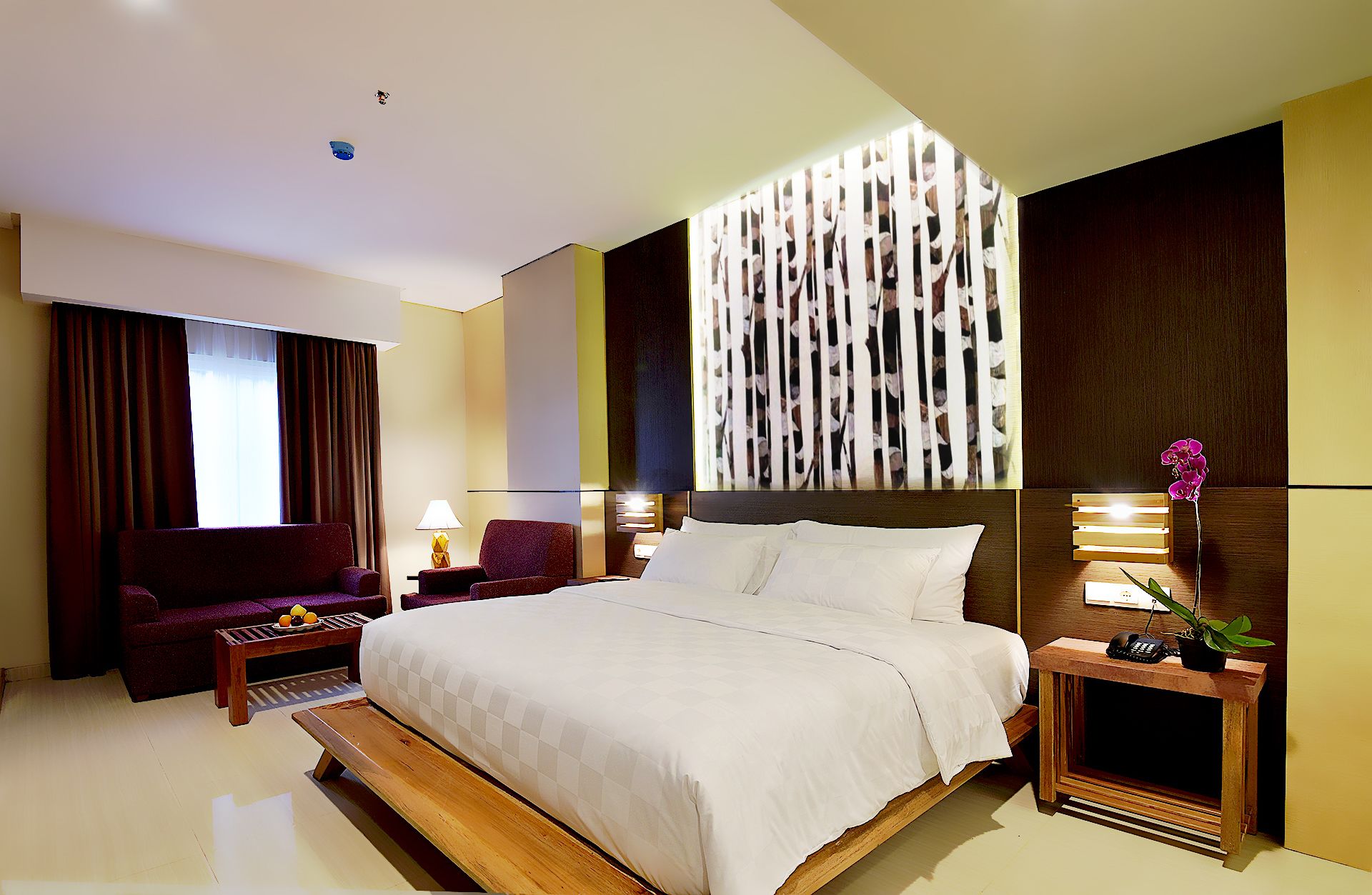 Une chambre d’hôtel avec un grand lit, un bureau, une chaise, une lampe et un panneau décoratif au mur.