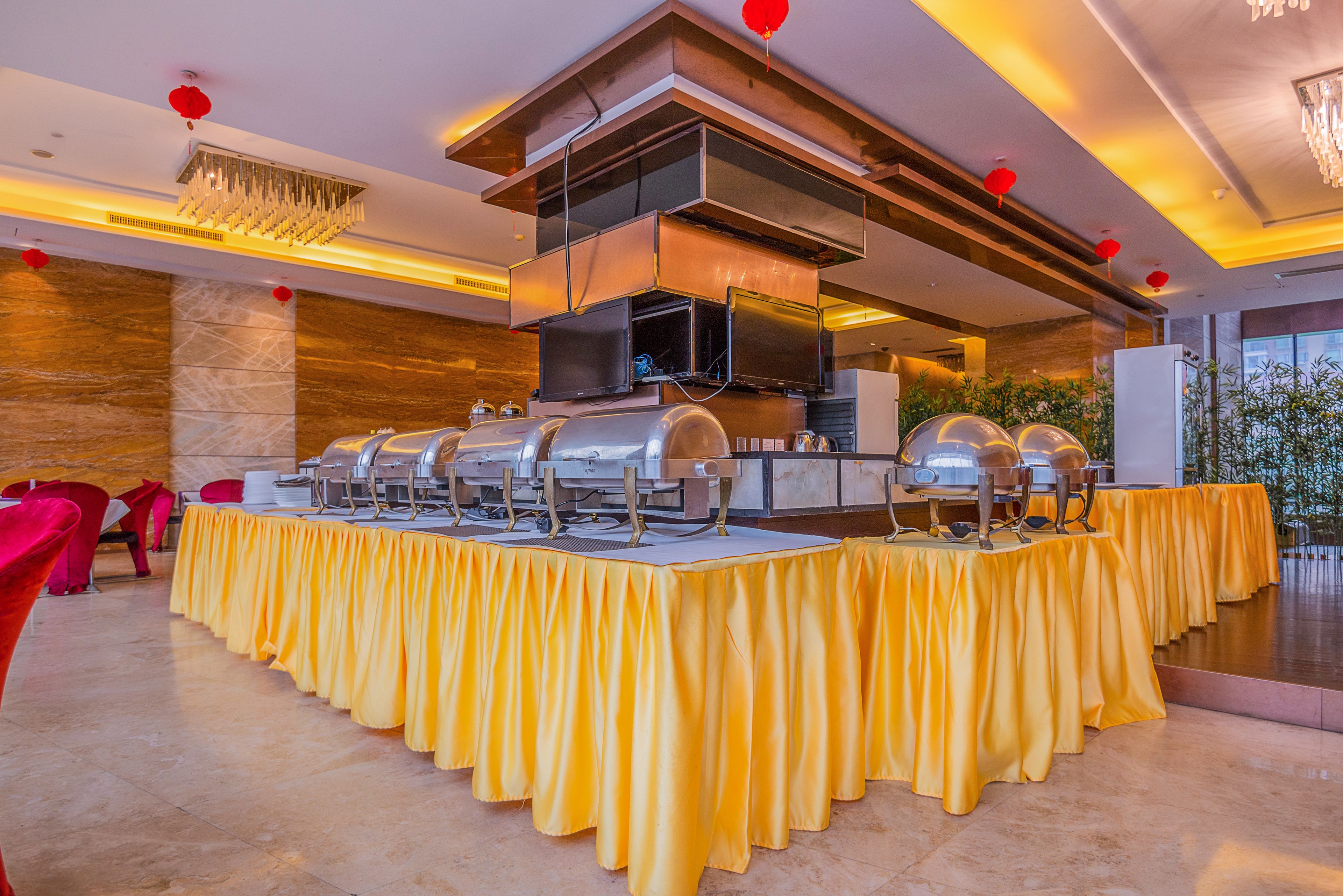 A buffet setup with multiple serving stations, a modern chandelier, and red lanterns on the ceiling.