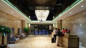 A hotel lobby with a reception desk, seating area, and a large chandelier. - Waifiden Apartment Pazhou Complex (Guangzhou)