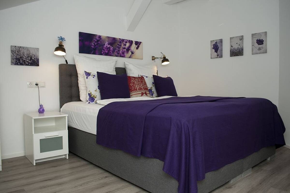 Ein Schlafzimmer mit Bett, Nachttisch in Weiß und Wandbild.