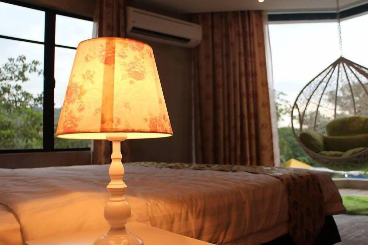 Un dormitorio con una cama, una silla colgante y una ventana con cortinas.