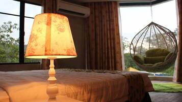 A bedroom with a bed, a hanging chair, and a window with curtains.