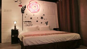 Un dormitorio con pared de ladrillo blanco, cama con ropa de cama blanca, mesita de noche con lámpara y decoración mural con estrellas y texto.