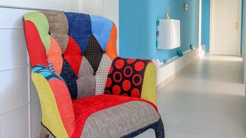 A brightly colored armchair with a geometric pattern, a white wall, and a blue accent wall in a hallway.