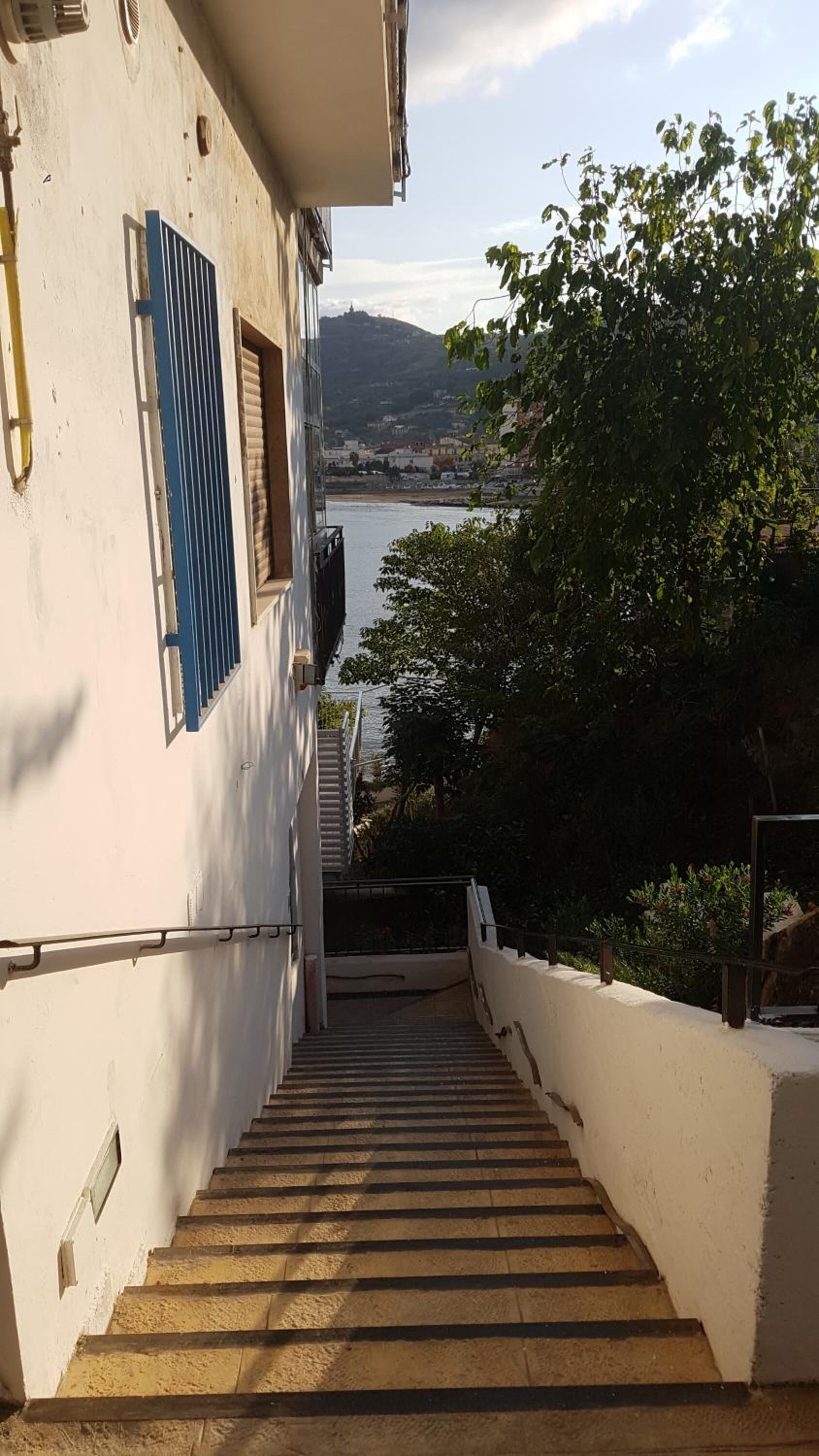 A staircase leading to a building with a view of a body of water and hills in the distance.