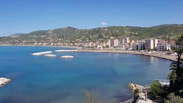 Una località costiera con un mare cristallino, scogliere frangiflutti ed edifici lungo la riva.