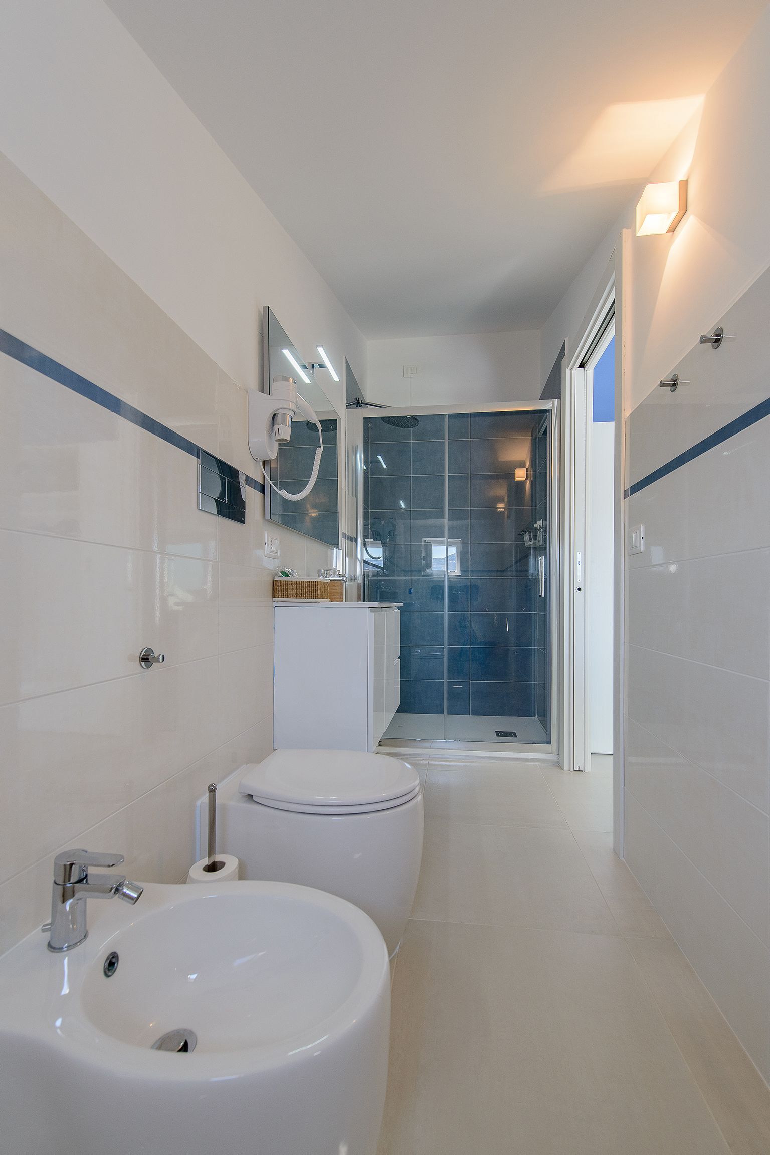 Een moderne badkamer met twee wastafels, een toilet, een douche en een douchecabine met glazen wanden.