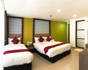 A hotel room with two beds, each with white bedding and red accents, a wooden headboard, and a patterned wall. - Check In Hotel (Kuala Lumpur)