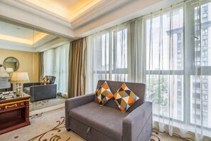 A hotel room with a sofa, a side table, a lamp, and a large window with curtains. - Liang an International Hotel (Hangzhou)
