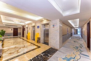 A hotel corridor with marble flooring, elevators, and a modern chandelier. - Liang an International Hotel (Hangzhou)