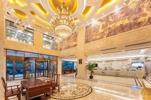 A hotel lobby with a reception desk, a chandelier, a large mirror, and a round carpet. - Liang an International Hotel (Hangzhou)