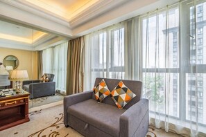 A hotel room with a sofa, a desk, a lamp, and large windows with curtains. - Liang an International Hotel (Hangzhou)