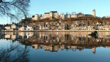 Een historisch kasteel met een gracht, gebouwen die in het water weerspiegelen, en een heldere lucht.