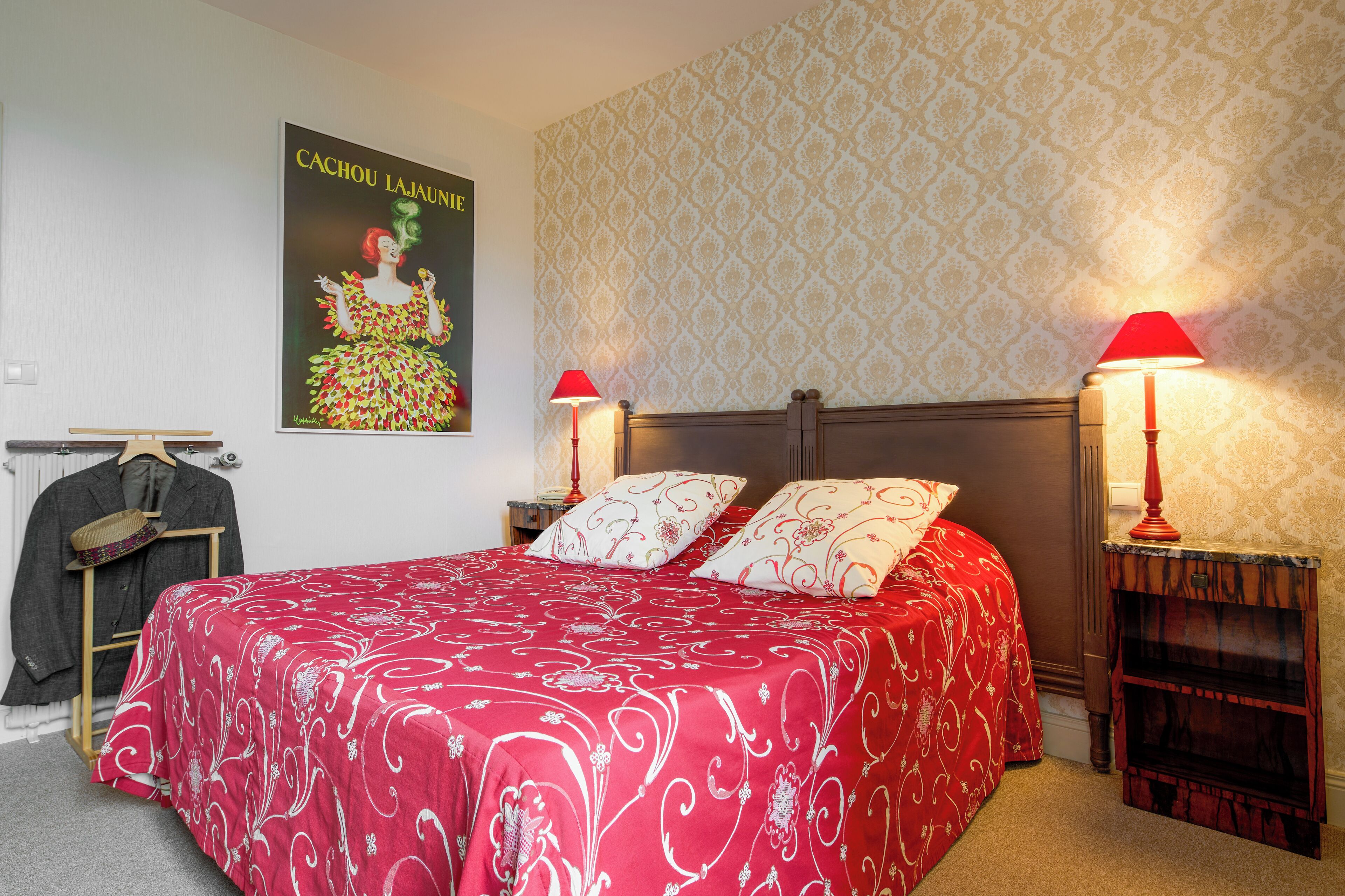A neatly arranged bedroom with a large bed, two bedside tables with lamps, a wardrobe, and a poster on the wall.