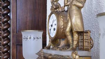 Un reloj decorativo con una figura tocando la batería, sobre un pedestal ornamentado.
