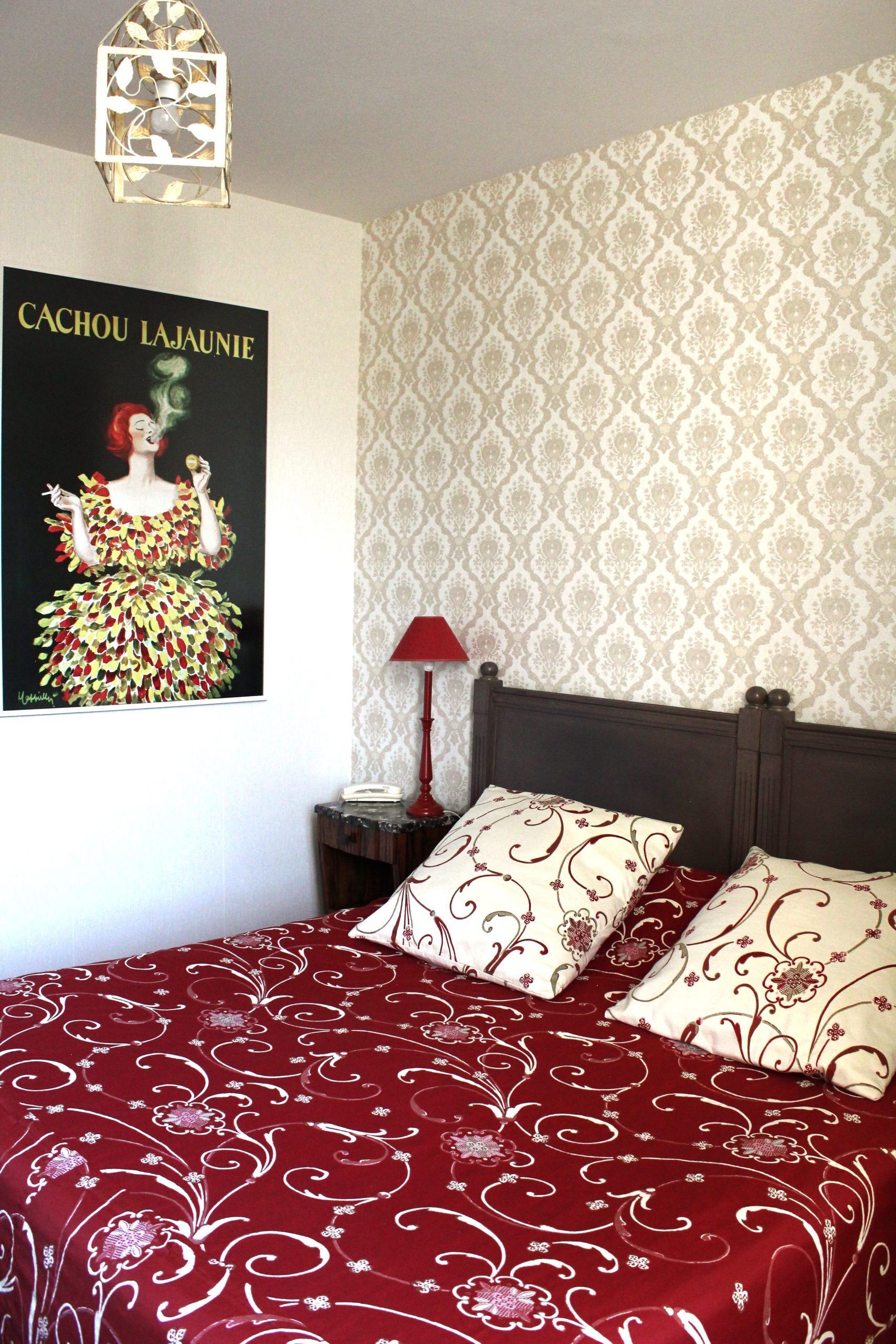 A bedroom with a bed, a nightstand, a lamp, and a poster on the wall.
