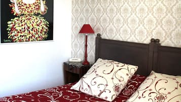 A bedroom with a bed, a nightstand, a lamp, and a poster on the wall.