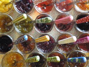 A display of various jams in glass jars with spoons. - Hôtel Diderot (Chinon)