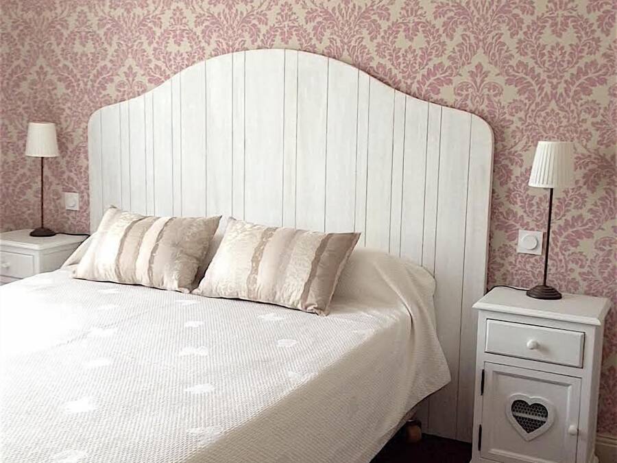 Un dormitorio con cama blanca, dos mesitas de noche y un papel tapiz estampado.
