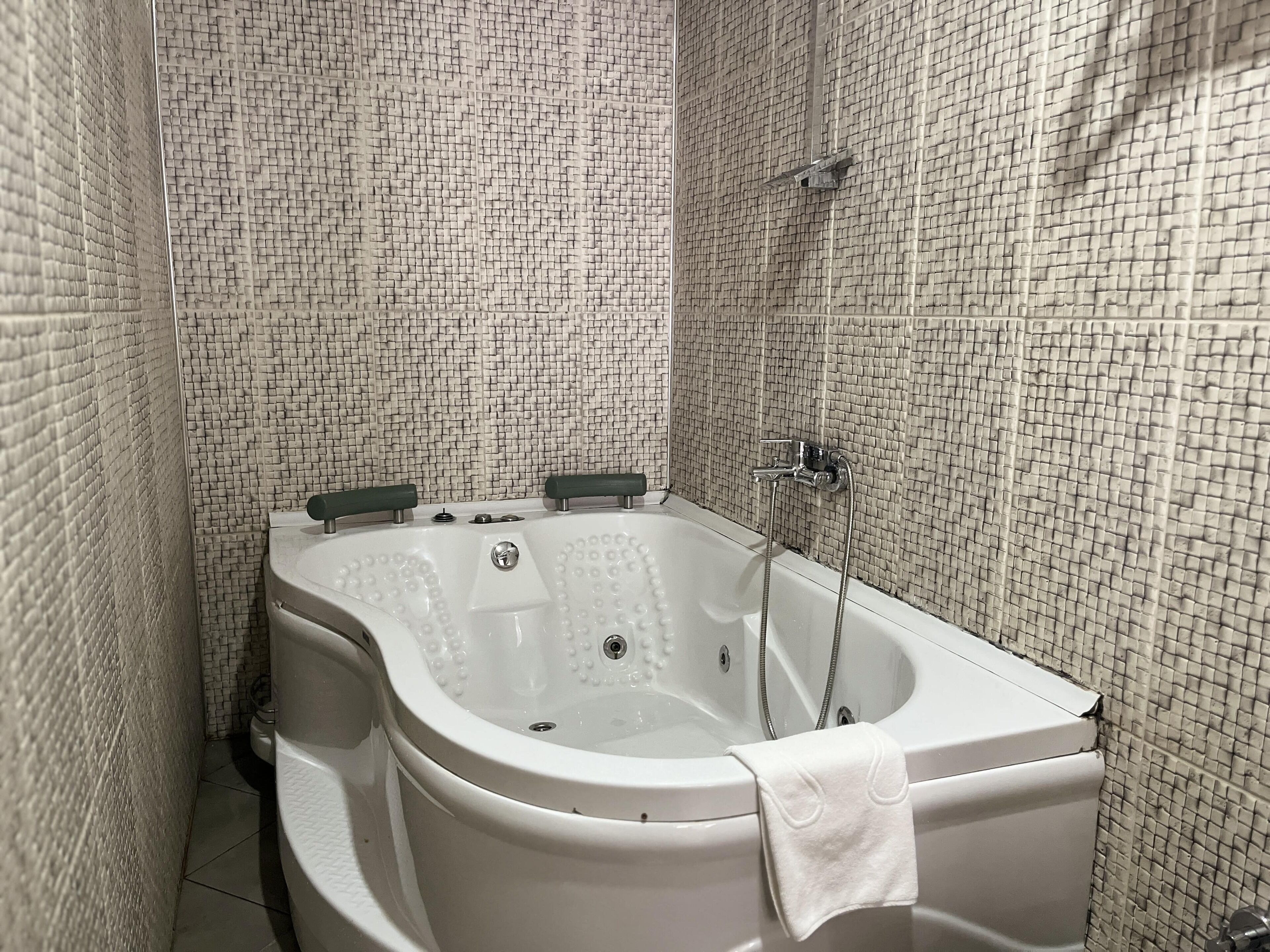 A bathroom with a freestanding bathtub, a shower area, and tiled walls.