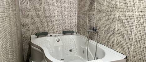 A bathroom with a freestanding bathtub, a shower area, and tiled walls.