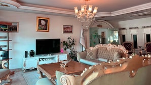 A luxurious living room with a large TV, ornate furniture, and a chandelier. - Ottoman Hotel Sakarya (Adapazari)
