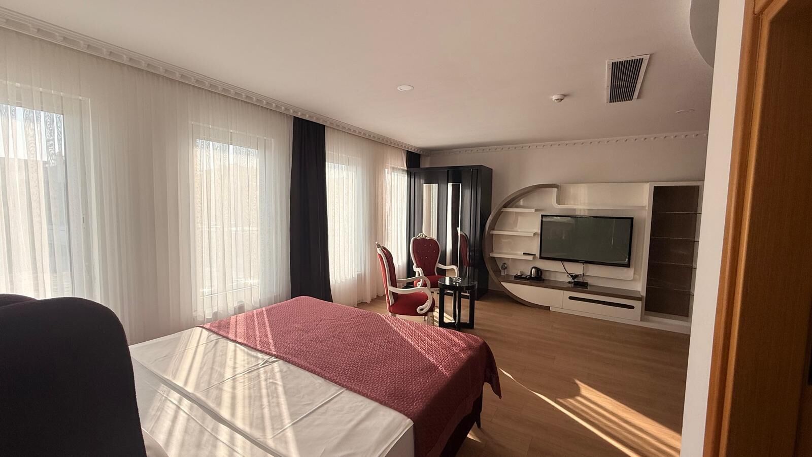 Una habitación de hotel con cama, televisor, escritorio y silla.