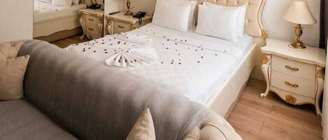 A hotel room with a large bed, a bedside table, a nightstand, and a mirror.