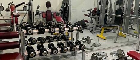 A gym with various exercise equipment, including dumbbells, benches, and weight machines.
